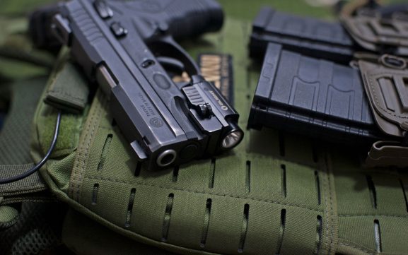 Handgun and loaded magazines placed on a tactical vest — range gear arranged for firearm training